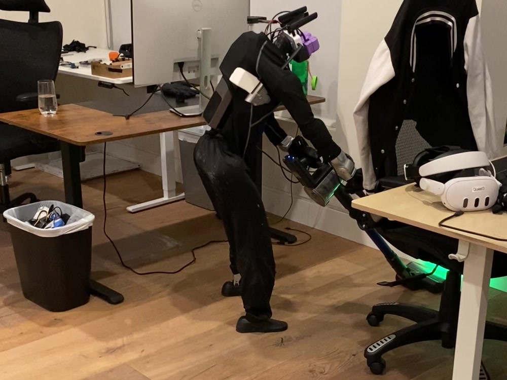Humanoid unit vacuuming an office floor between desks